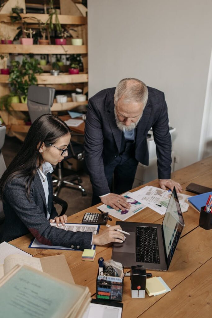 Business professionals collaborating over documents and laptop in a modern office.